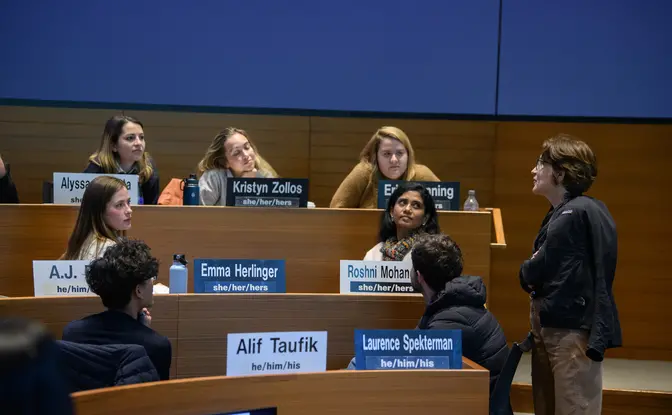 A professor talking with students in a classroom