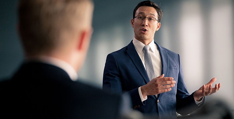 Image of man dressed in a business suit speaking in front of another man
