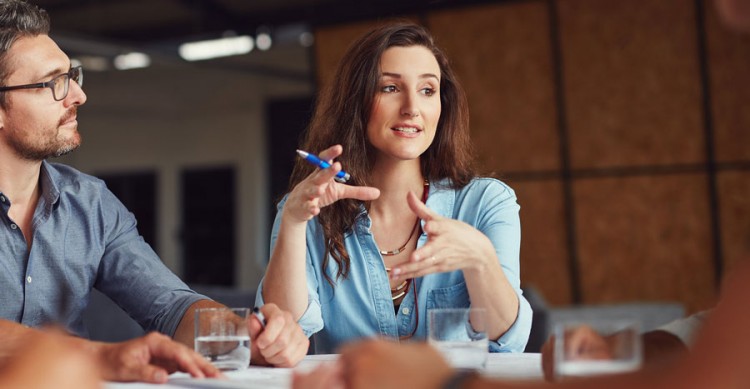 Group of people around a table while woman talks