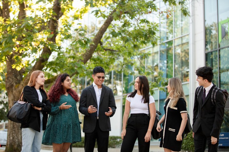 Six students talking outside of the UBC Sauder building