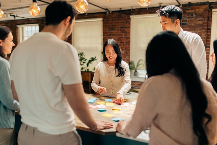 Image of five people gathered around a table of sticky notes