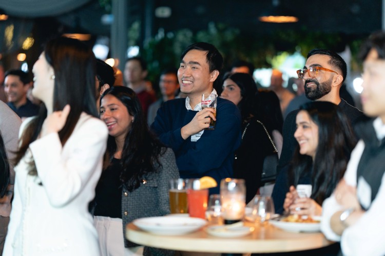 A group of UBC Sauder alumni enjoying drinks and refreshments at a mixer
