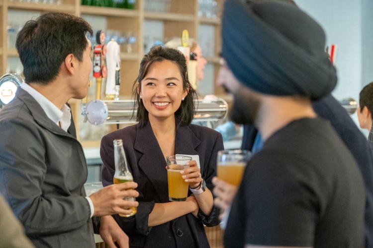A group of Alumni standing around socialisng and drinking